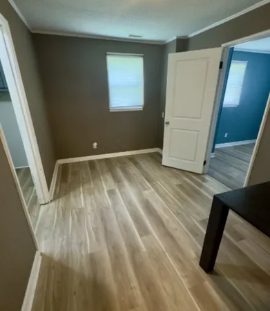 a view of an empty room with wooden floor and stairs