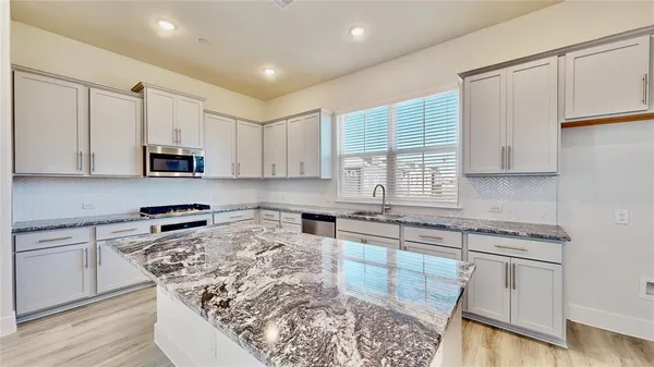 a kitchen with stainless steel appliances granite countertop a stove a sink and a microwave