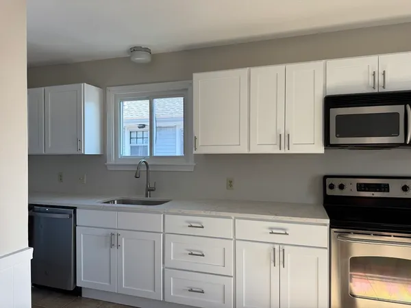 a kitchen with granite countertop white cabinets and a stove top oven