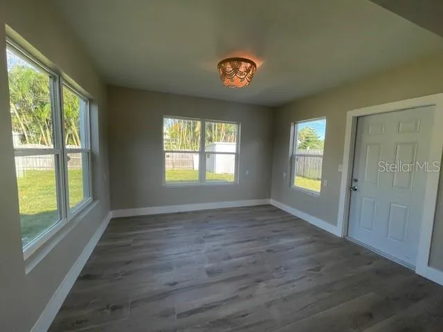 a view of an empty room with a window and wooden floor