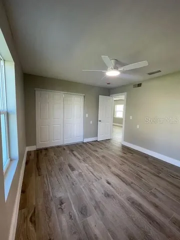 an empty room with wooden floor and windows
