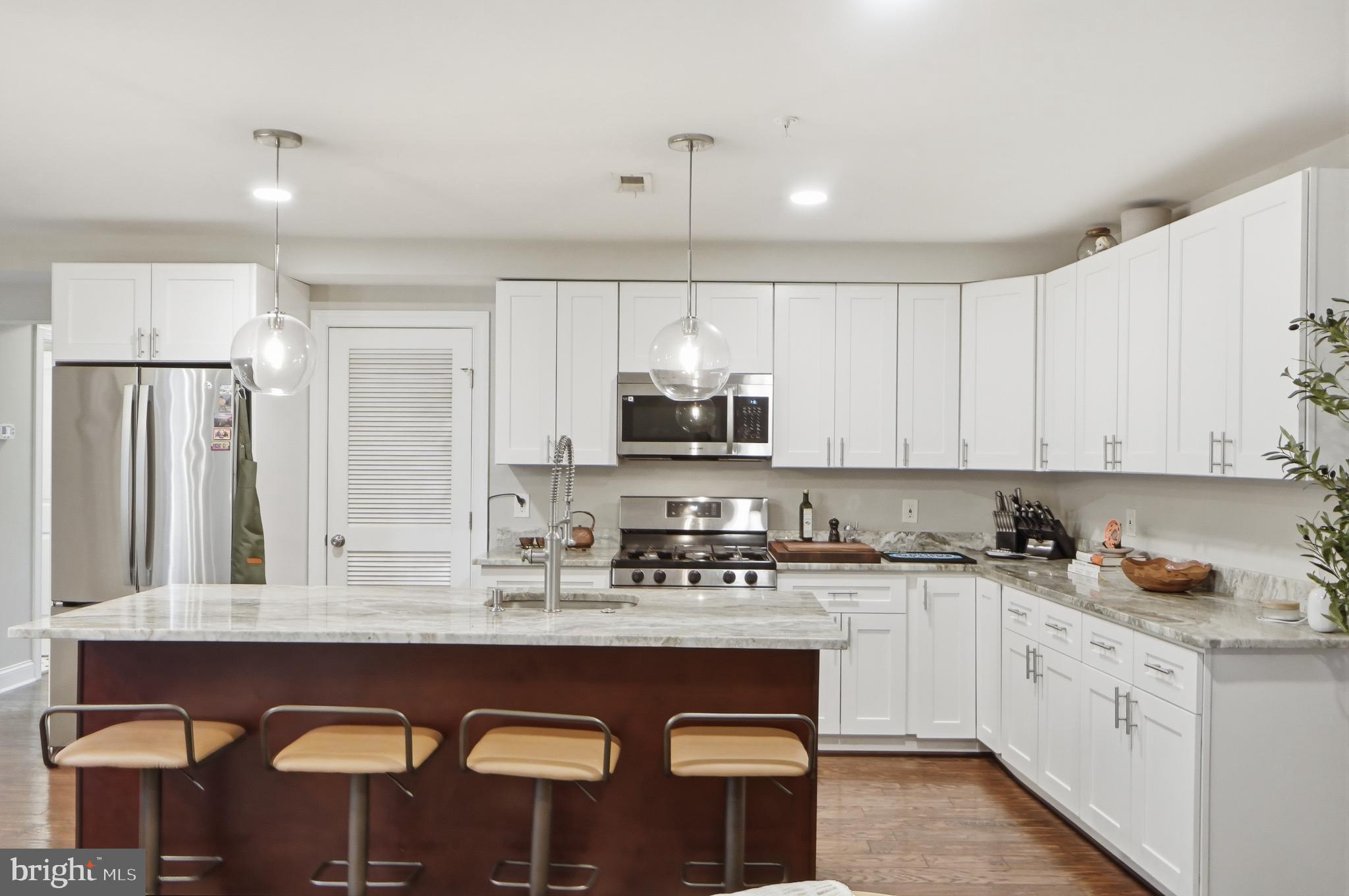1258 Holbrook Terrace Northeast, Unit 5 Washington, DC 20002 - Photo 8 of 25 a kitchen with stainless steel appliances granite countertop a sink a stove a refrigerator cabinets and a dining table with wooden floor