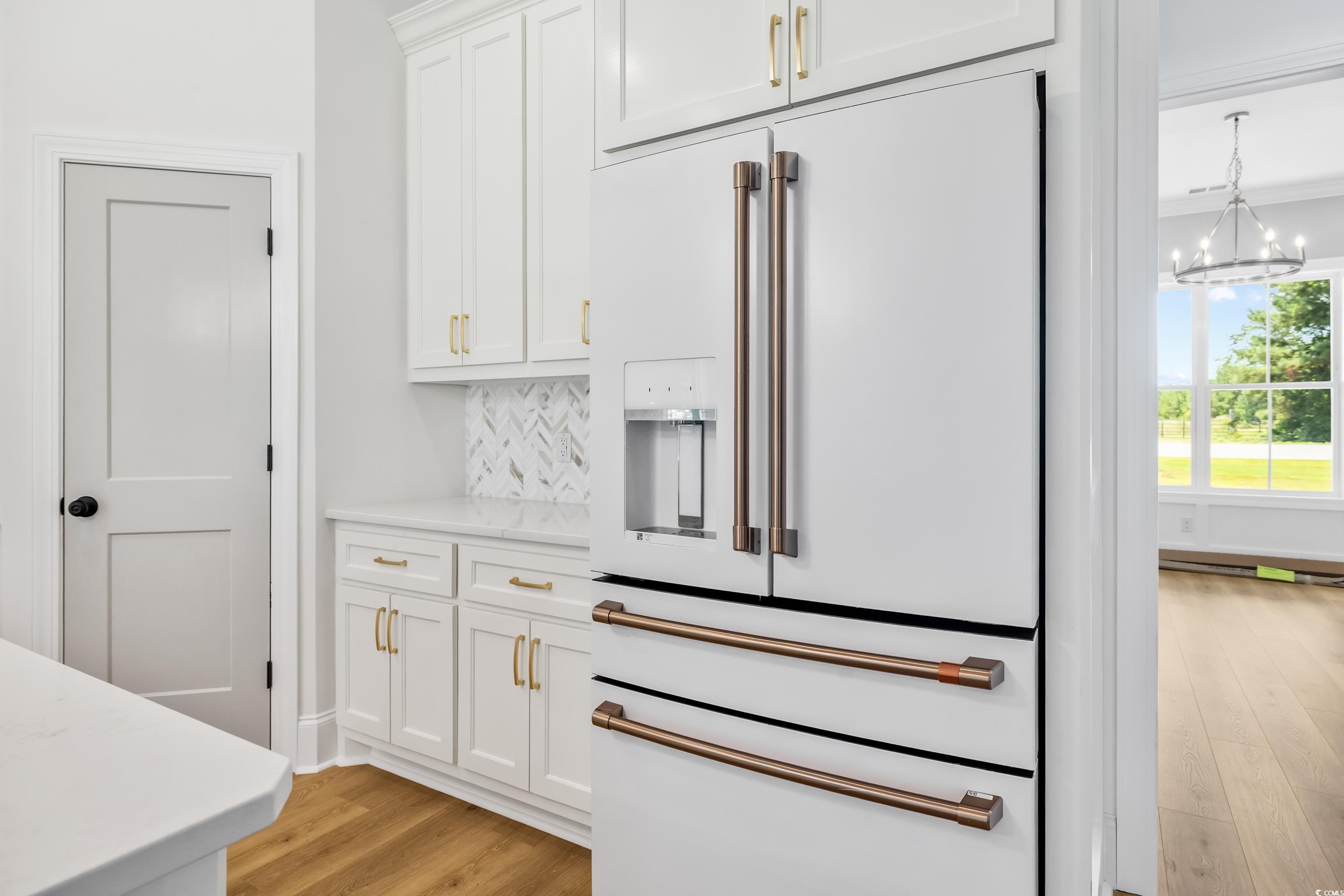 346 Ridge Road Galivants Ferry, SC 29544 - Photo 10 of 24 Kitchen with high end white refrigerator, white cabinetry, light wood finished floors, and a chandelier