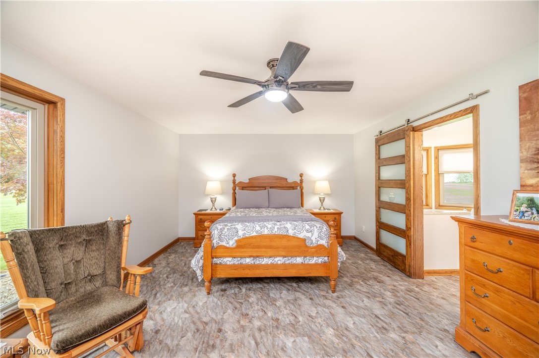 405 Airport Road Northwest Warren, OH 44481 - Photo 22 of 50 Spacious bedroom featuring ceiling fan with integrated lighting, and a barn door with frosted glass panels leading into master bathroom