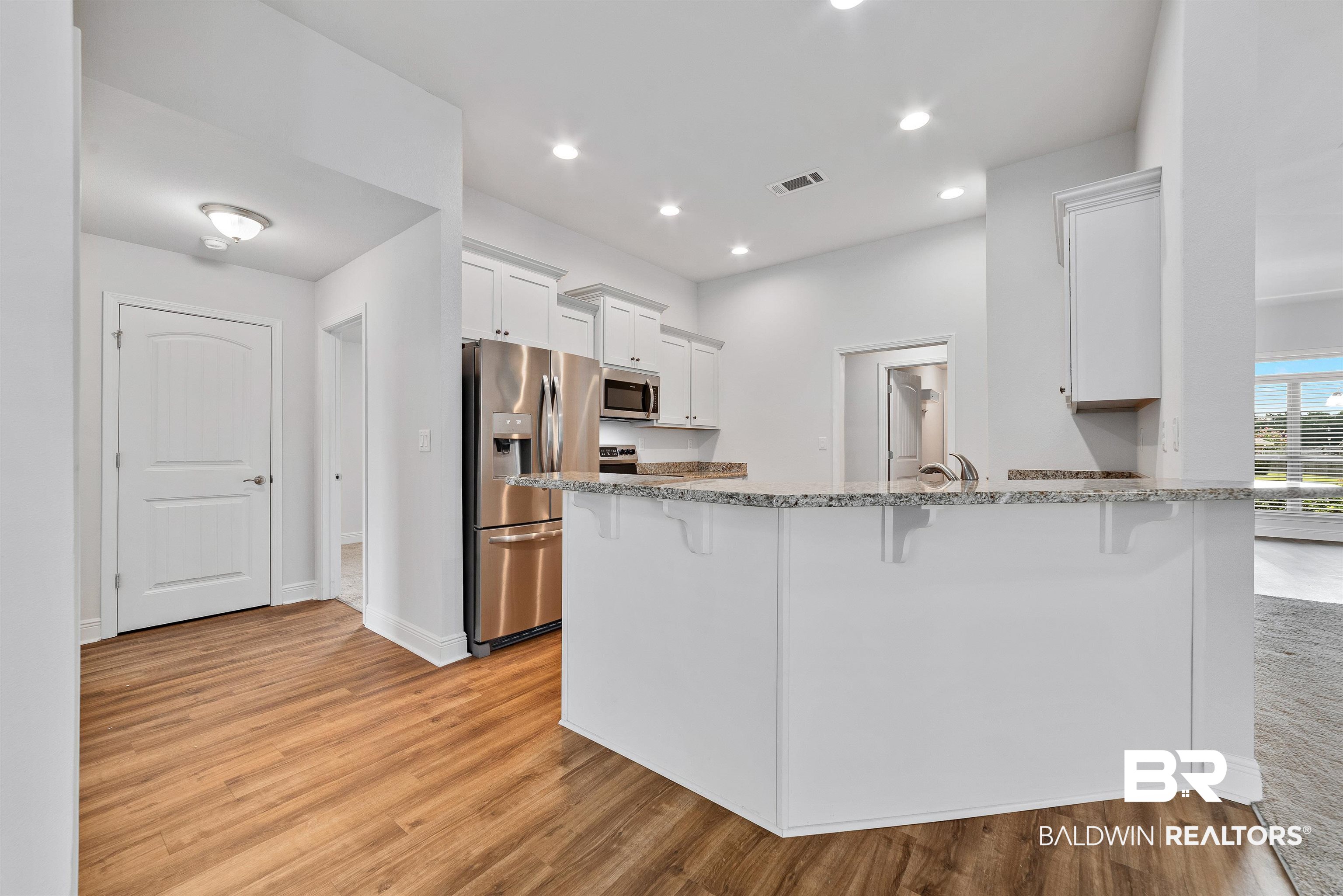 13155 Wishbone Court Foley, AL 36535 - Photo 16 of 39 Kitchen with kitchen peninsula, white cabinets, light stone counters, light hardwood / wood-style floors, and appliances with stainless steel finishes