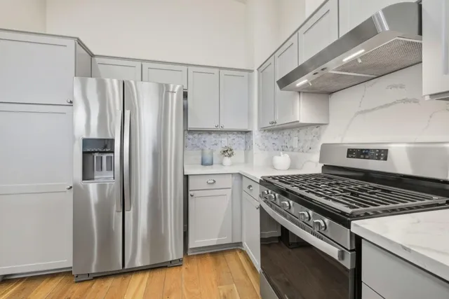 a kitchen with stainless steel appliances a refrigerator a sink and wooden floors