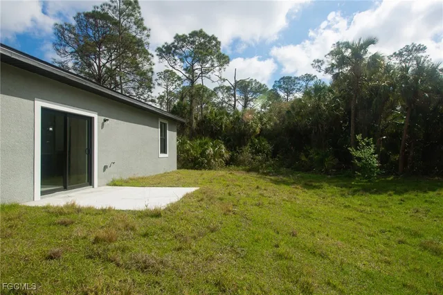 a backyard of a house with plants and large trees