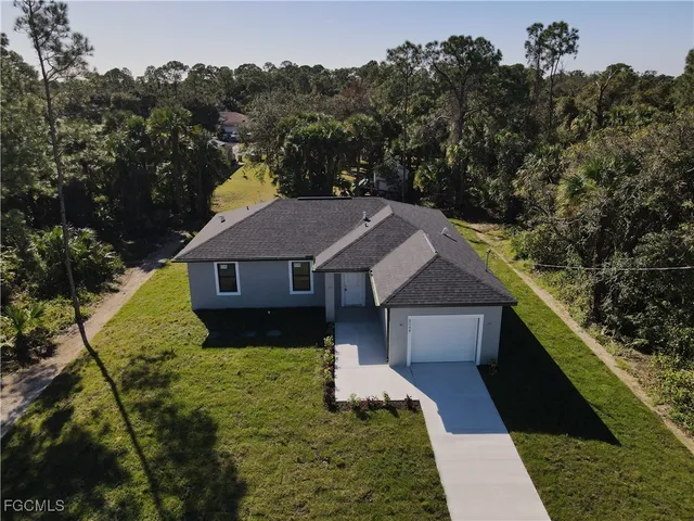 a aerial view of a house next to a yard with large trees