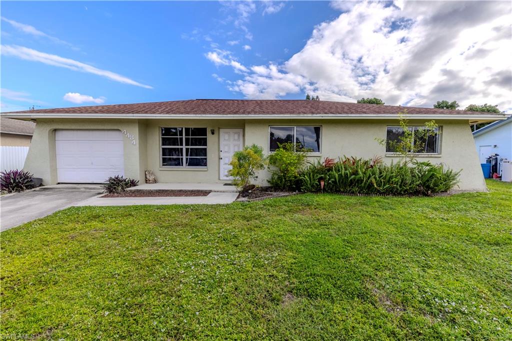 4484 30th Place Southwest Naples, FL 34116 - Photo 1 of 20 Ranch-style house featuring stucco siding, a front lawn, concrete driveway, and a garage