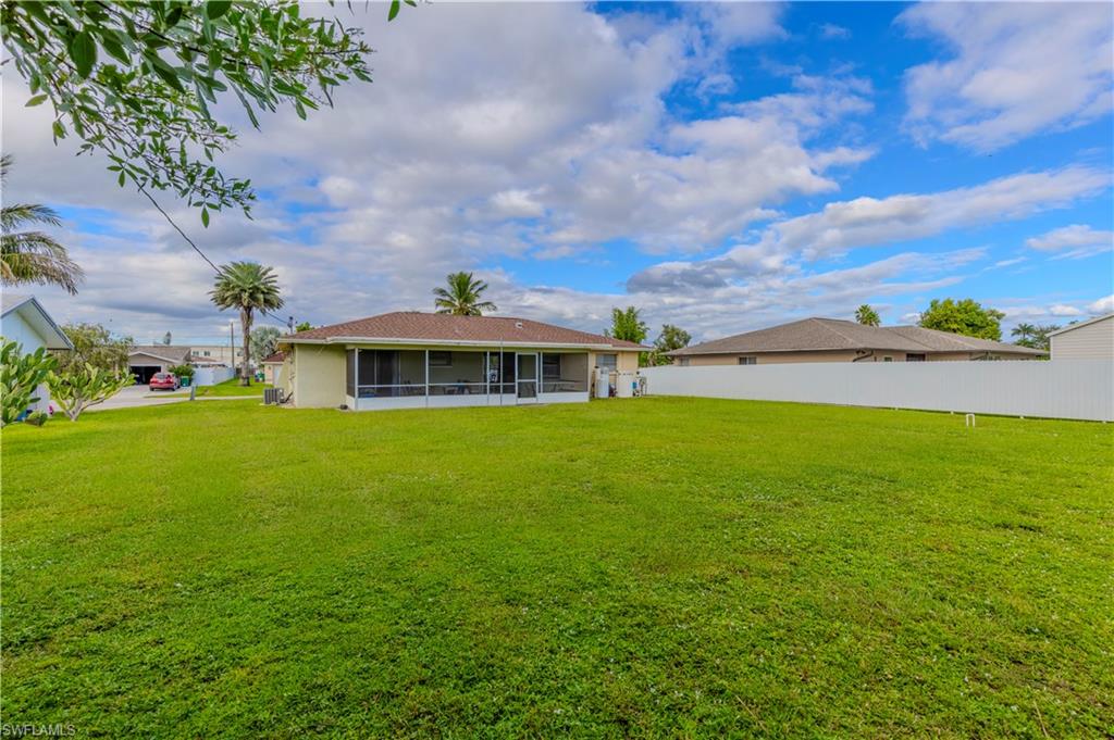 4484 30th Place Southwest Naples, FL 34116 - Photo 18 of 20 Rear view of property featuring a yard and a sunroom