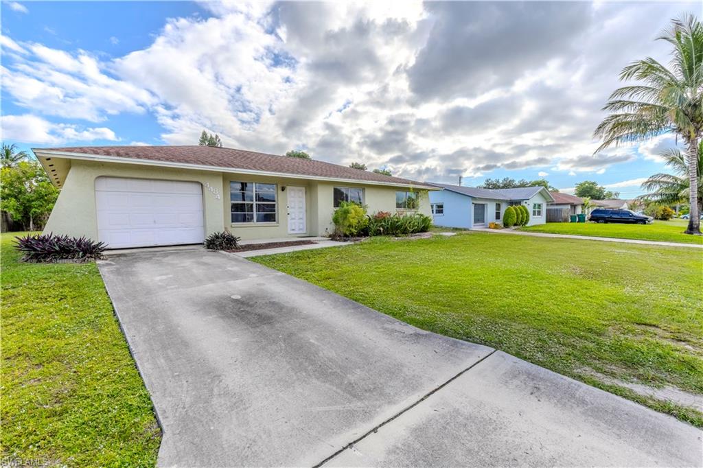 4484 30th Place Southwest Naples, FL 34116 - Photo 4 of 20 Ranch-style house featuring stucco siding, driveway, a front yard, and a garage