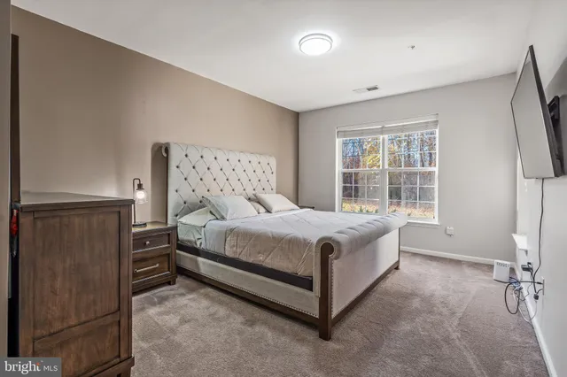 a bed sitting in a spacious bedroom next to a window
