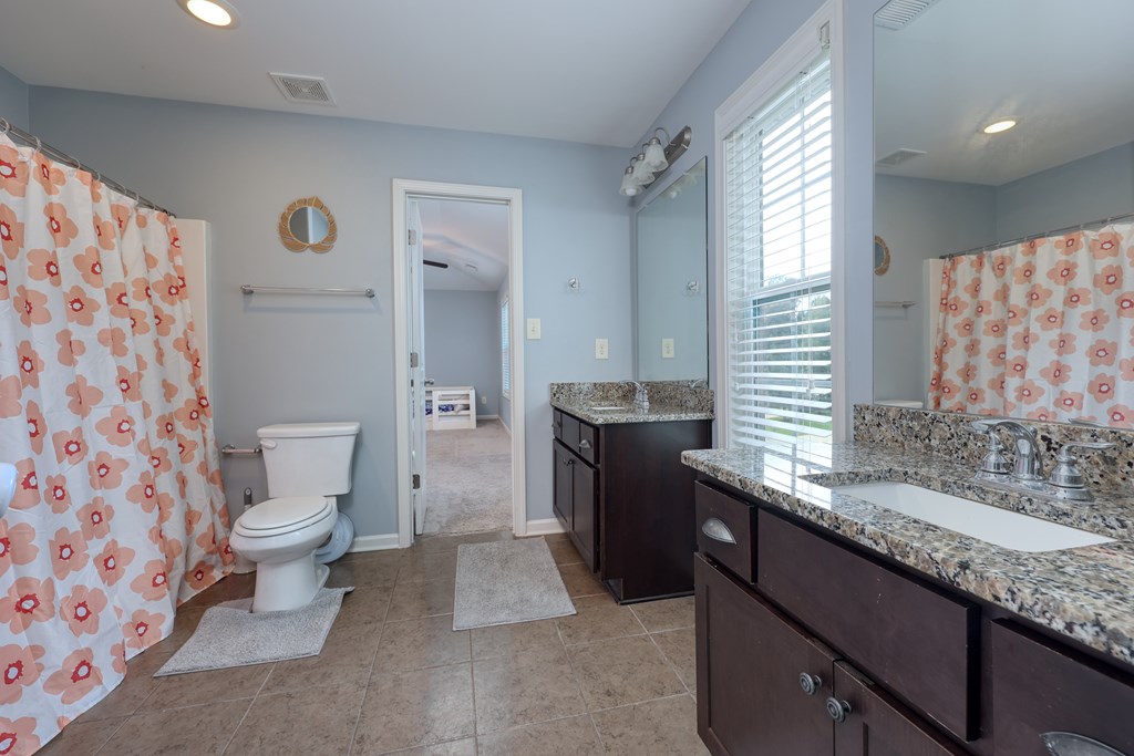 98 Valley Bluff Drive Hamilton, GA 31811 - Photo 24 of 35 a bathroom with a granite countertop sink a toilet a mirror and shower curtain