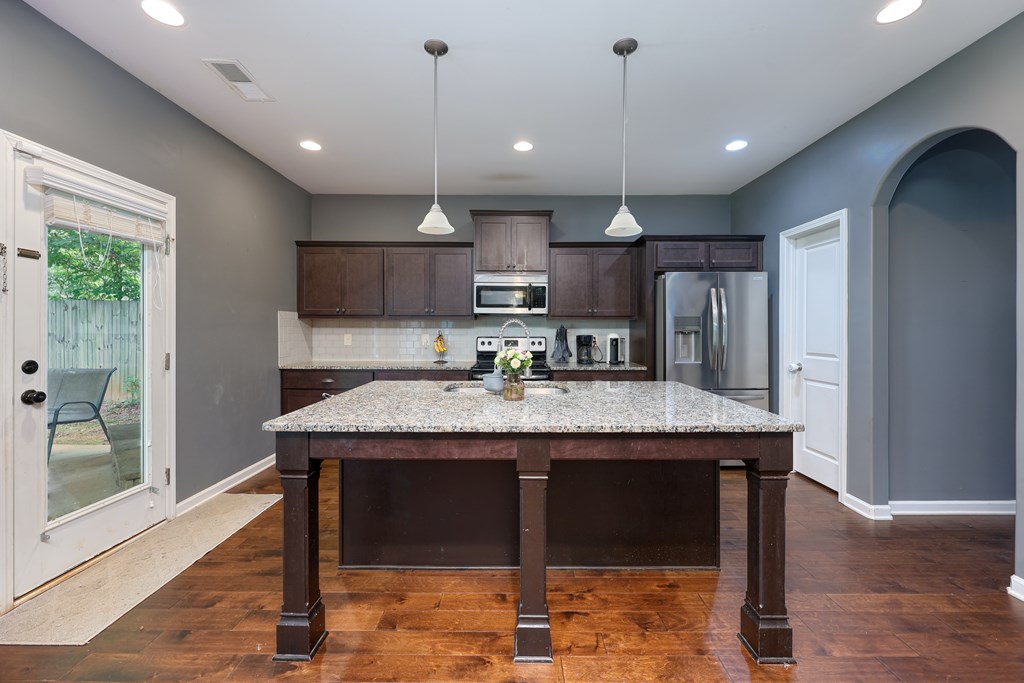 98 Valley Bluff Drive Hamilton, GA 31811 - Photo 5 of 35 a kitchen with stainless steel appliances granite countertop a table chairs refrigerator and microwave