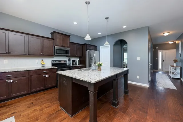 a kitchen with granite countertop a stove a sink a refrigerator and wooden cabinets