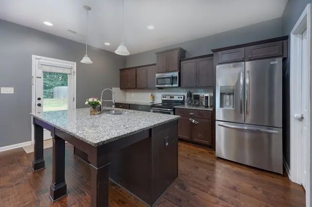 a kitchen with stainless steel appliances granite countertop a refrigerator a stove a sink dishwasher and microwave oven with wooden floor