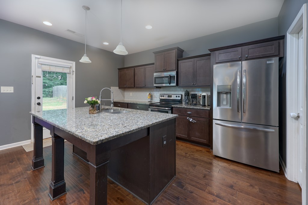 98 Valley Bluff Drive Hamilton, GA 31811 - Photo 7 of 35 a kitchen with stainless steel appliances granite countertop a refrigerator a stove a sink dishwasher and microwave oven with wooden floor