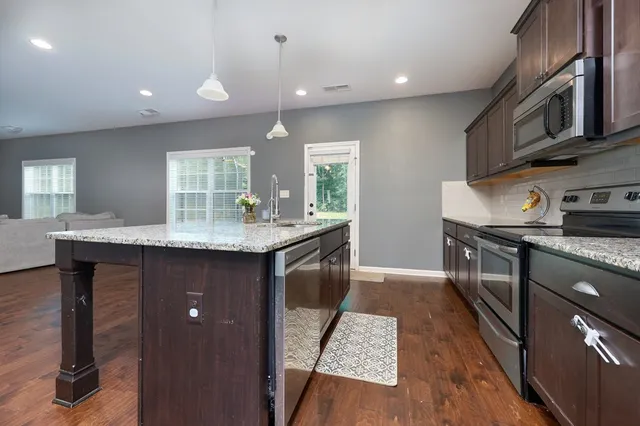 a kitchen with kitchen island granite countertop a sink stove and cabinets