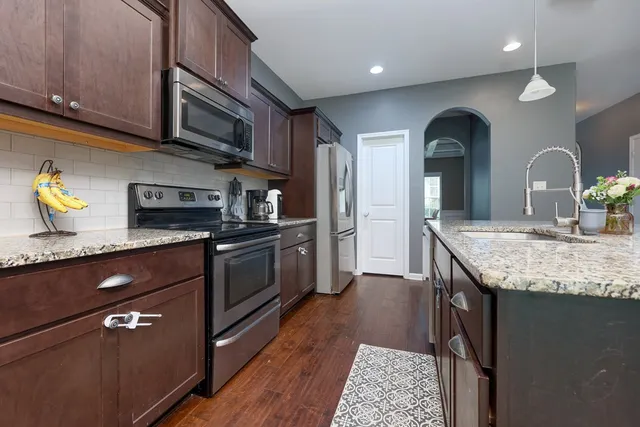 a kitchen with stainless steel appliances granite countertop a stove a sink and a microwave