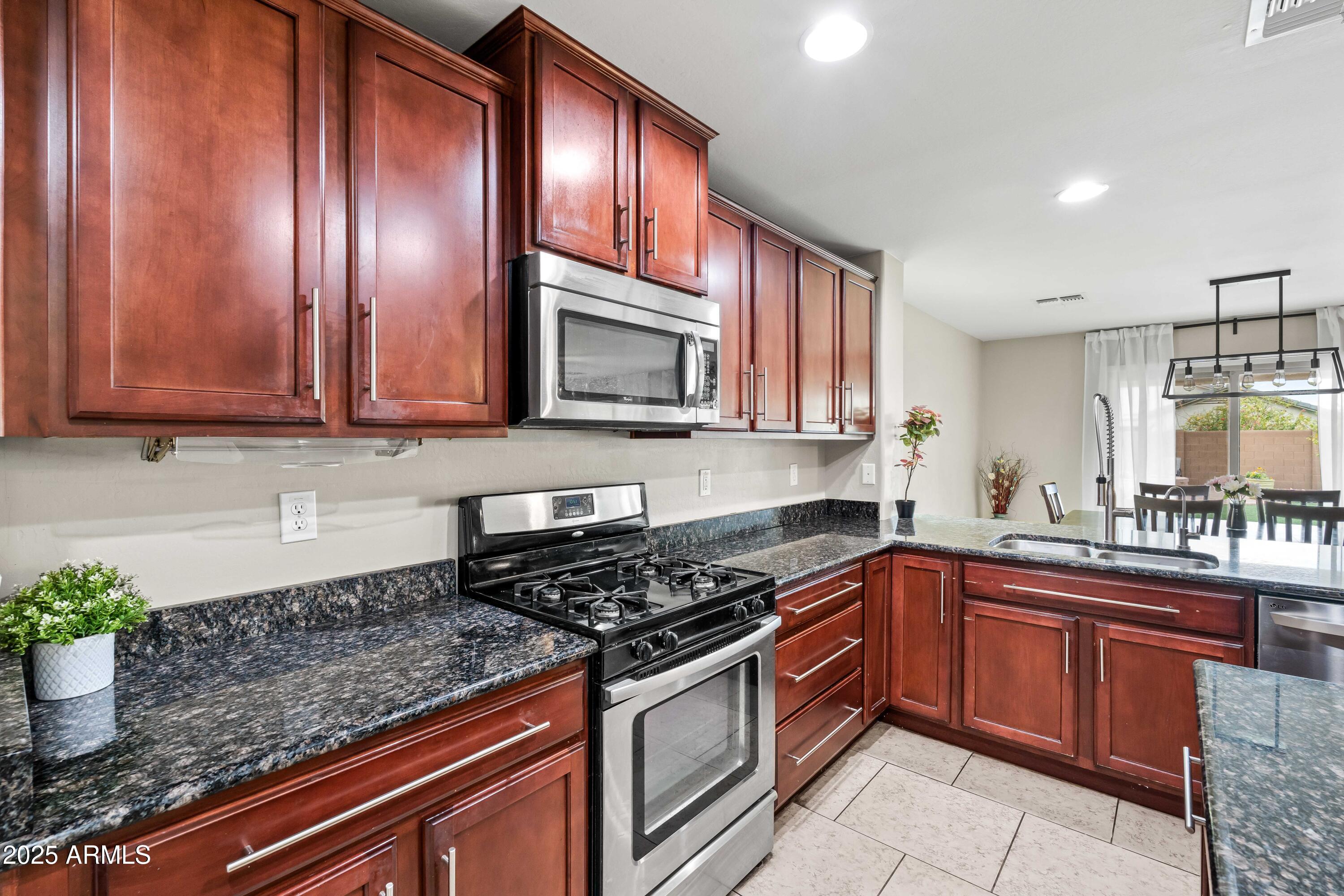 6525 West Georgetown Way Florence, AZ 85132 - Photo 18 of 82 a kitchen with stainless steel appliances granite countertop wooden cabinets a stove top oven a sink and dishwasher