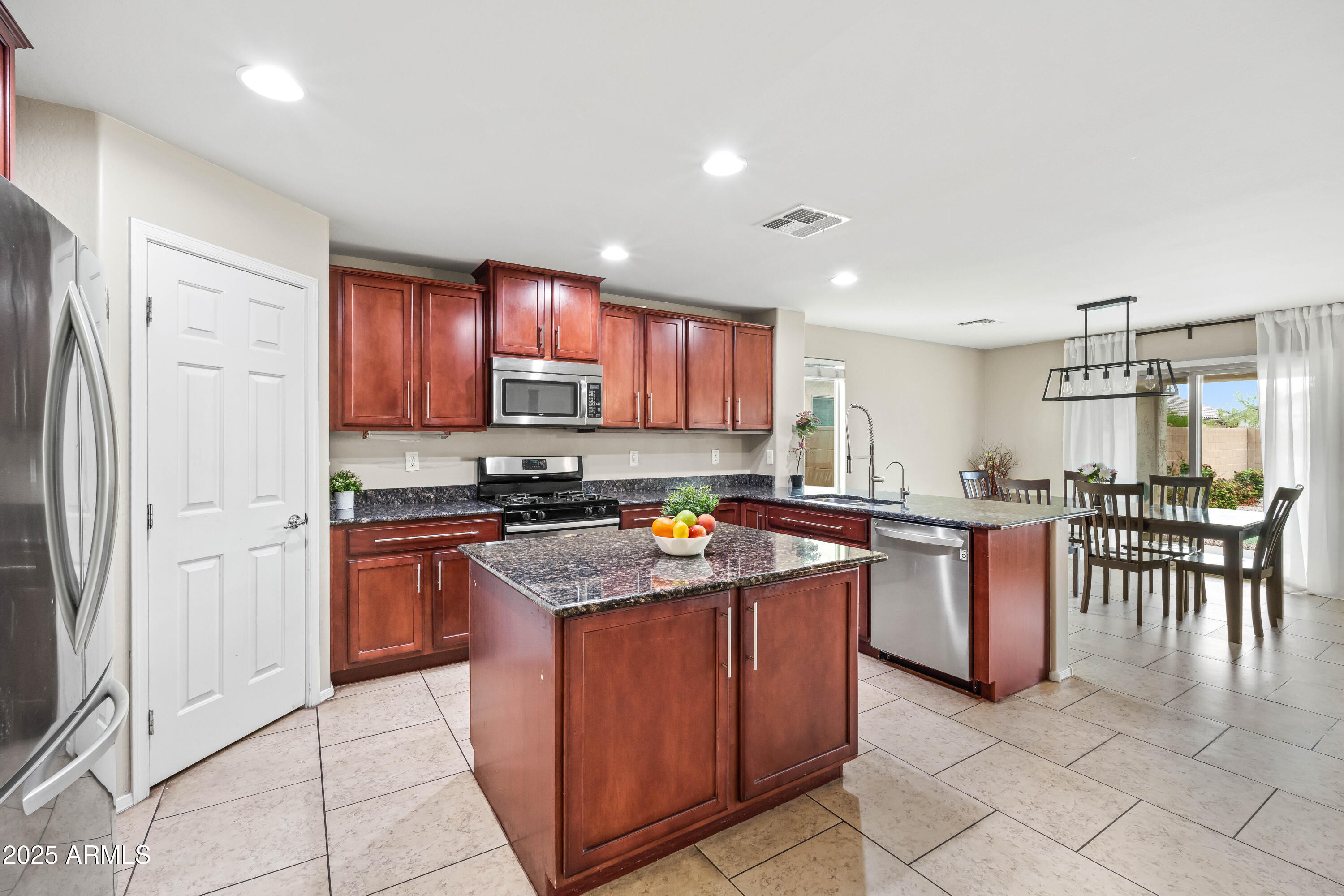 6525 West Georgetown Way Florence, AZ 85132 - Photo 3 of 82 a kitchen with stainless steel appliances granite countertop a stove top oven a sink a dining table and chairs