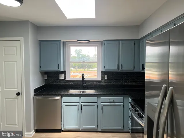 a kitchen with granite countertop a sink a stove and a microwave