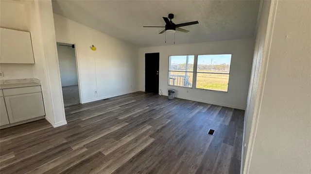 a view of empty room with wooden floor and fan