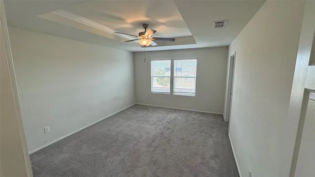 an empty room with chandelier fan and windows