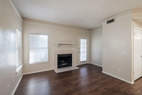 an empty room with wooden floor a fireplace and windows