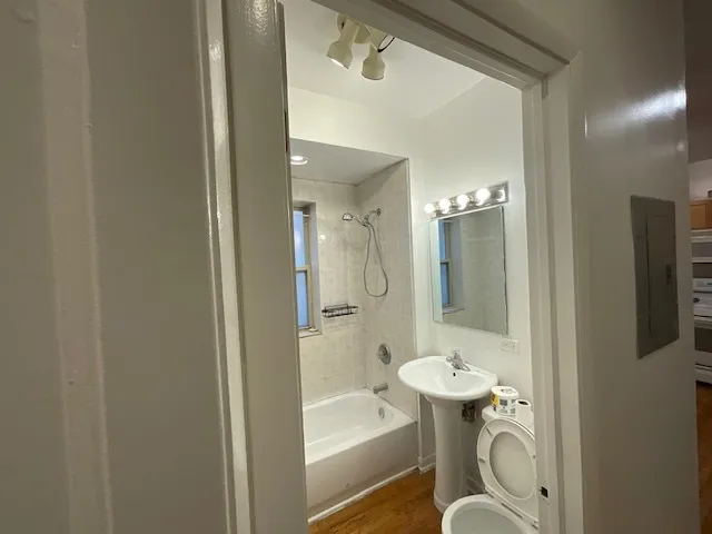 a bathroom with a bathtub shower sink mirror and toilet