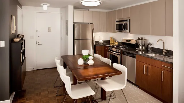 a kitchen with stainless steel appliances a refrigerator a stove a sink a dining table and chairs