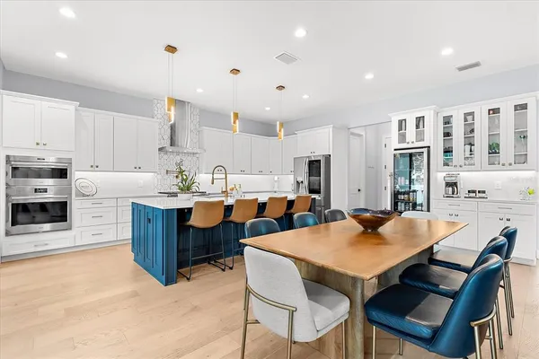 a large kitchen with stainless steel appliances kitchen island a large counter top a sink a stove and a refrigerator