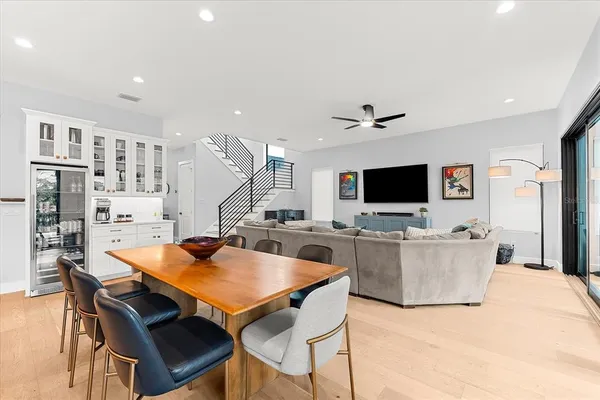 a dining room with stainless steel appliances kitchen island granite countertop a dining table chairs and a refrigerator