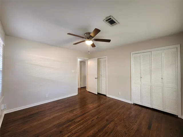 an empty room with wooden floor and ceiling fan