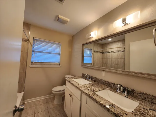a bathroom with a granite countertop sink toilet and a mirror