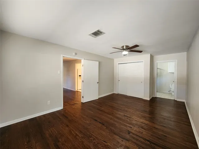 a view of empty room with wooden floor and ceiling fan