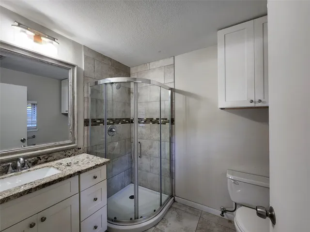 a bathroom with a granite countertop sink toilet and shower