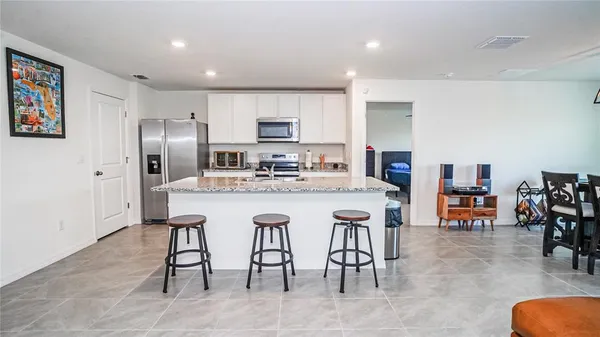 a kitchen with stainless steel appliances granite countertop a kitchen island a stove a refrigerator a sink a dining table and chairs