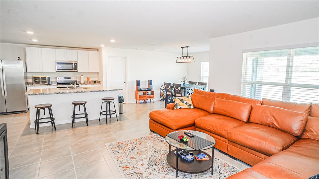 13253 Mylion Way Spring Hill, FL 34610 - Photo 9 of 31 a living room with furniture a rug and kitchen view