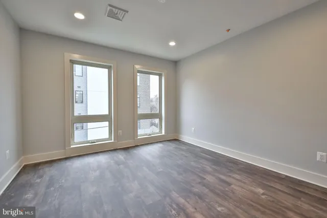 an empty room with wooden floor and windows
