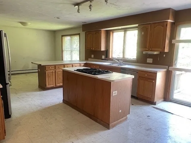 a kitchen with stainless steel appliances granite countertop a stove a sink a refrigerator and a window