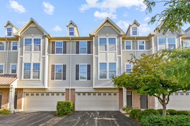 a front view of a residential apartment building with a yard and potted plants
