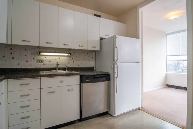 a kitchen with granite countertop white cabinets and refrigerator