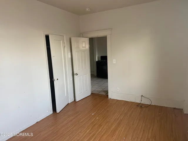 a view of an empty room with wooden floor and closet
