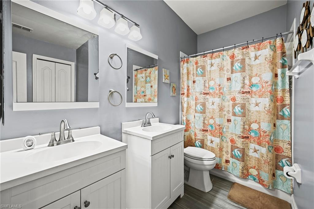 21684 Brixham Run Loop Estero, FL 33928 - Photo 11 of 26 Bathroom with curtained shower, two vanities, and dark wood-type flooring