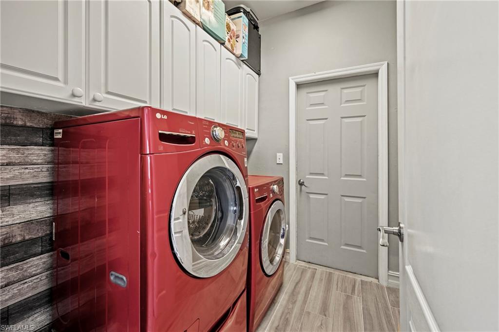 21684 Brixham Run Loop Estero, FL 33928 - Photo 21 of 26 Washroom featuring cabinet space, wood finish floors, and washer and clothes dryer
