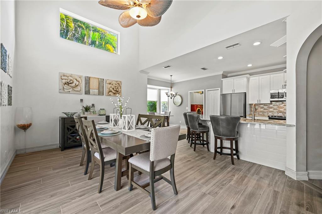 21684 Brixham Run Loop Estero, FL 33928 - Photo 4 of 26 Dining area with recessed lighting, wood tiled floors, a towering ceiling, ornamental molding, and arched walkways