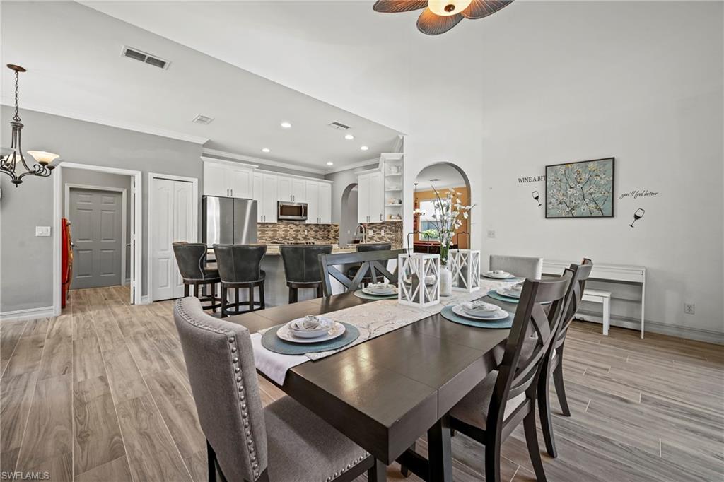 21684 Brixham Run Loop Estero, FL 33928 - Photo 8 of 26 Dining space with a chandelier, light wood-type flooring, arched walkways, recessed lighting, and ornamental molding
