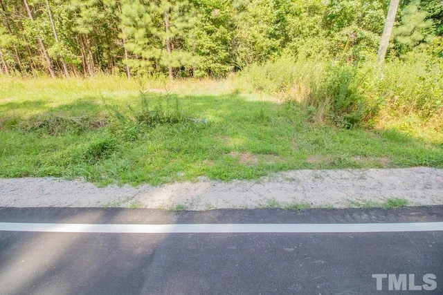 a view of a yard with flower plants and wooden fence