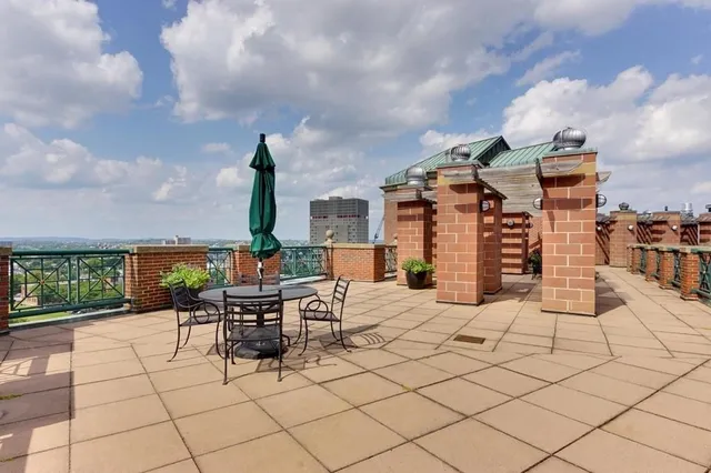 a roof deck with table and chairs and potted plants